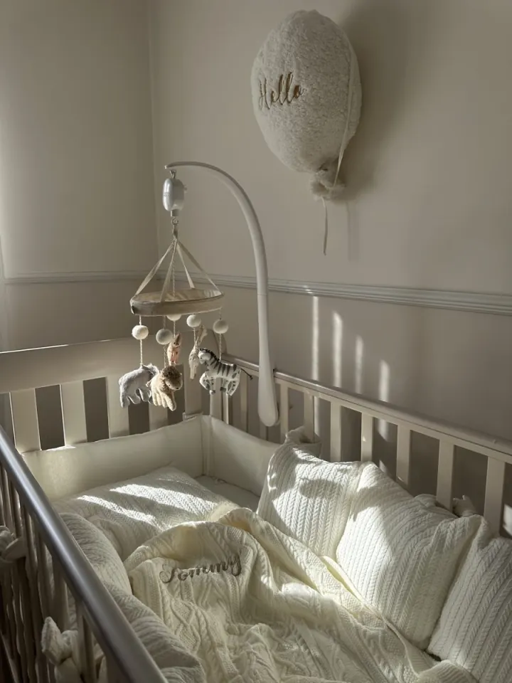 Tommy’s crib with a knitted blanket and an animal mobile