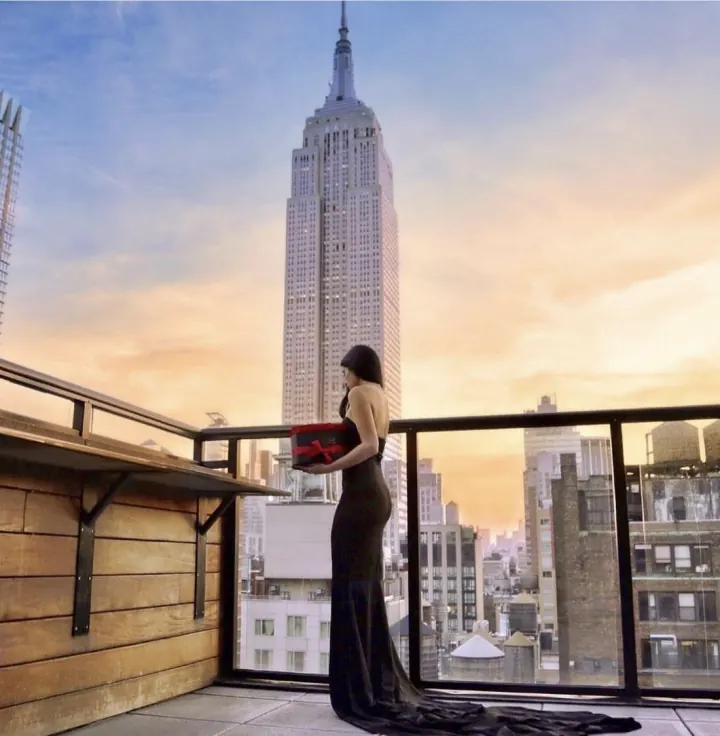 Shani in a black gown on a New York rooftop facing the Empire State Building